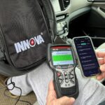 Innova 5610 CarScan Pro OBD2 scanner being used to check a hybrid vehicle's battery system.