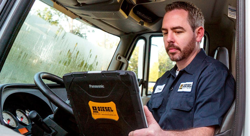 Technician using a laptop to diagnose a truck