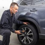 Technician using a TPMS scan tool on a vehicle.