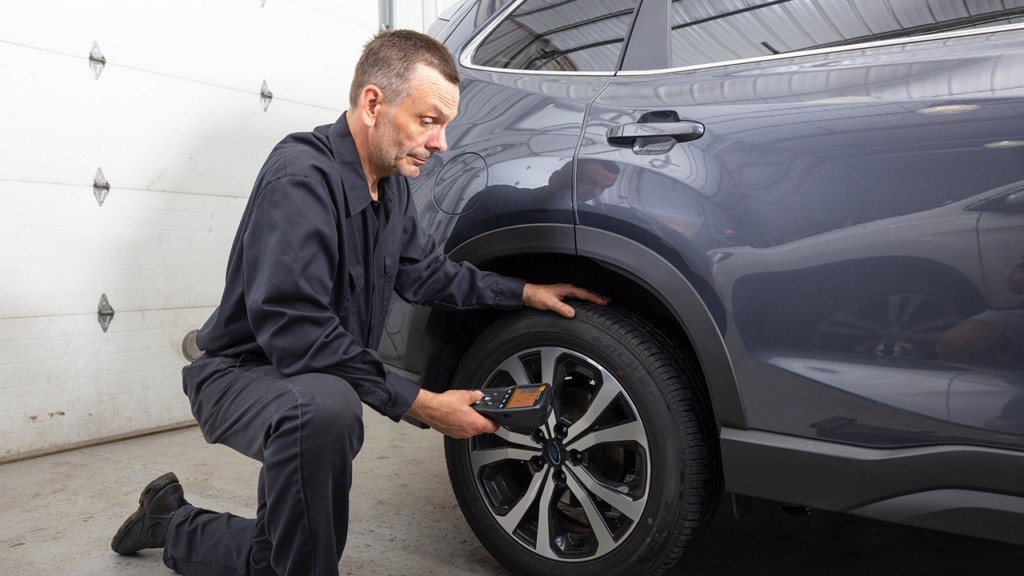 Technician using a TPMS scan tool on a vehicle.